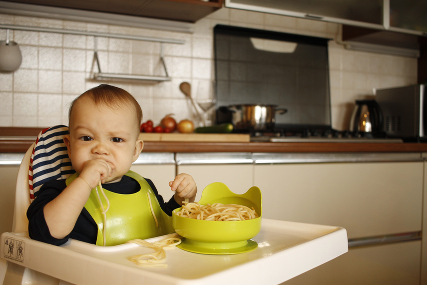 baby eating spaghetti on highchair